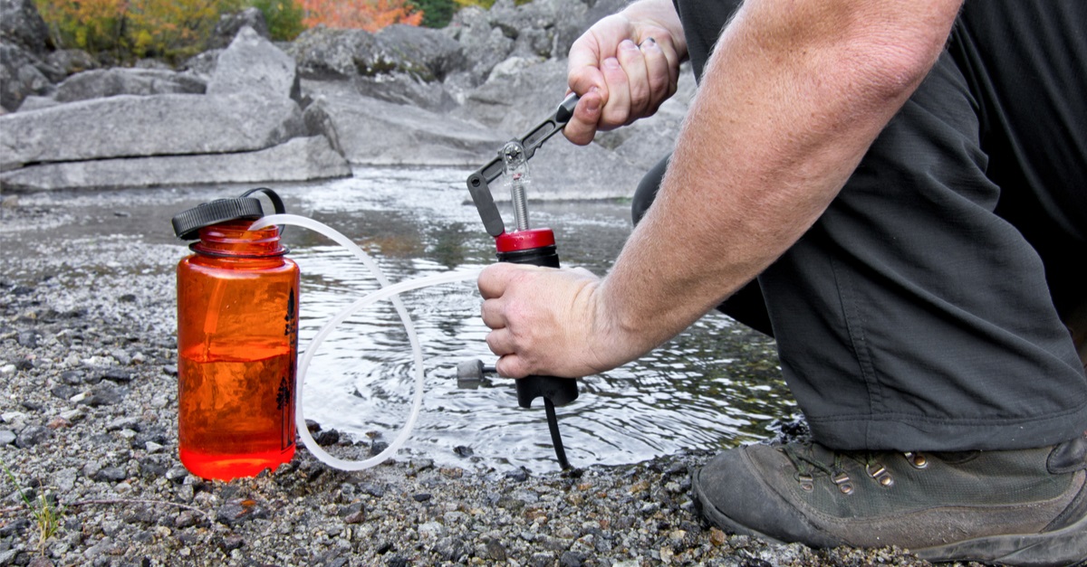 person uses a lightweight compact water filter to pump safe drinking water