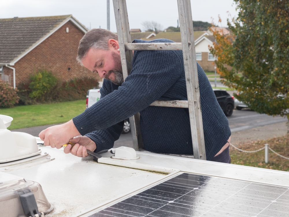 Man Installing Solar Panel on Roof of RV